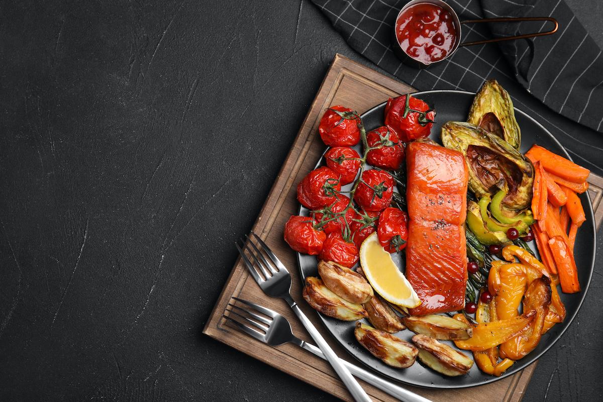 Article Cards Featured Image Tasty cooked salmon and vegetables served on black table, flat lay with space for text. Healthy meals from air fryer