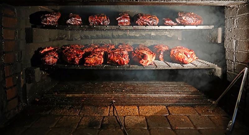 A restaurant barbecue oven full of cooking meat.