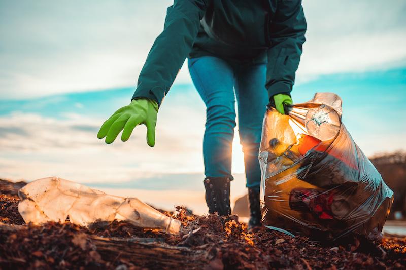 World Oceans Day showing a volunteer cleaning trash from a beach