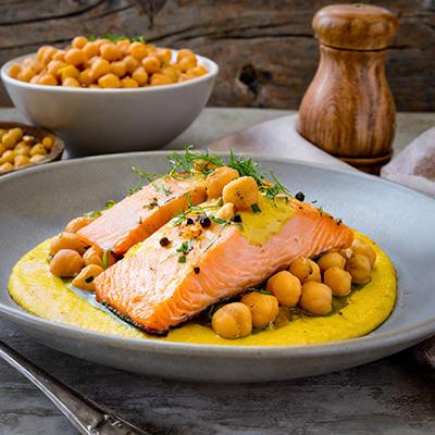 Fish sauces with saffron and chickpeas underneath filets of cooked fish.